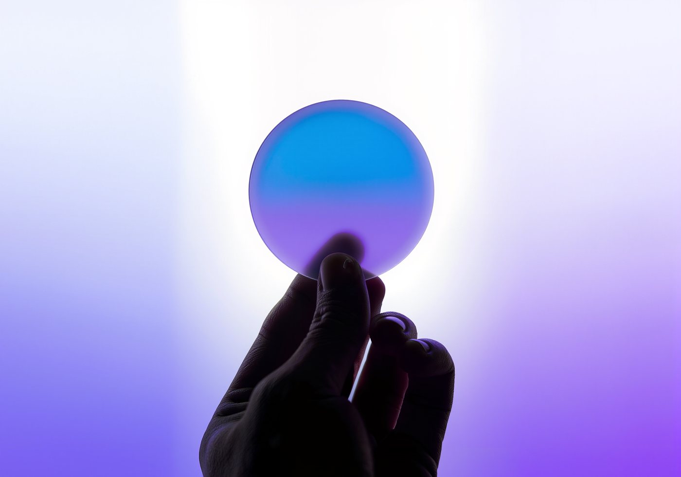 A hand balancing a glass disc on a fingertip
